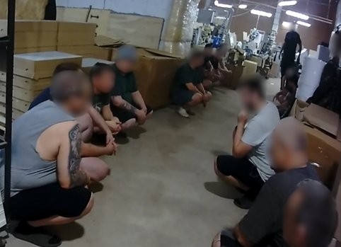 Abās telpas malās zemē tup vairāki cilvēki ar aizsegtām sejām
