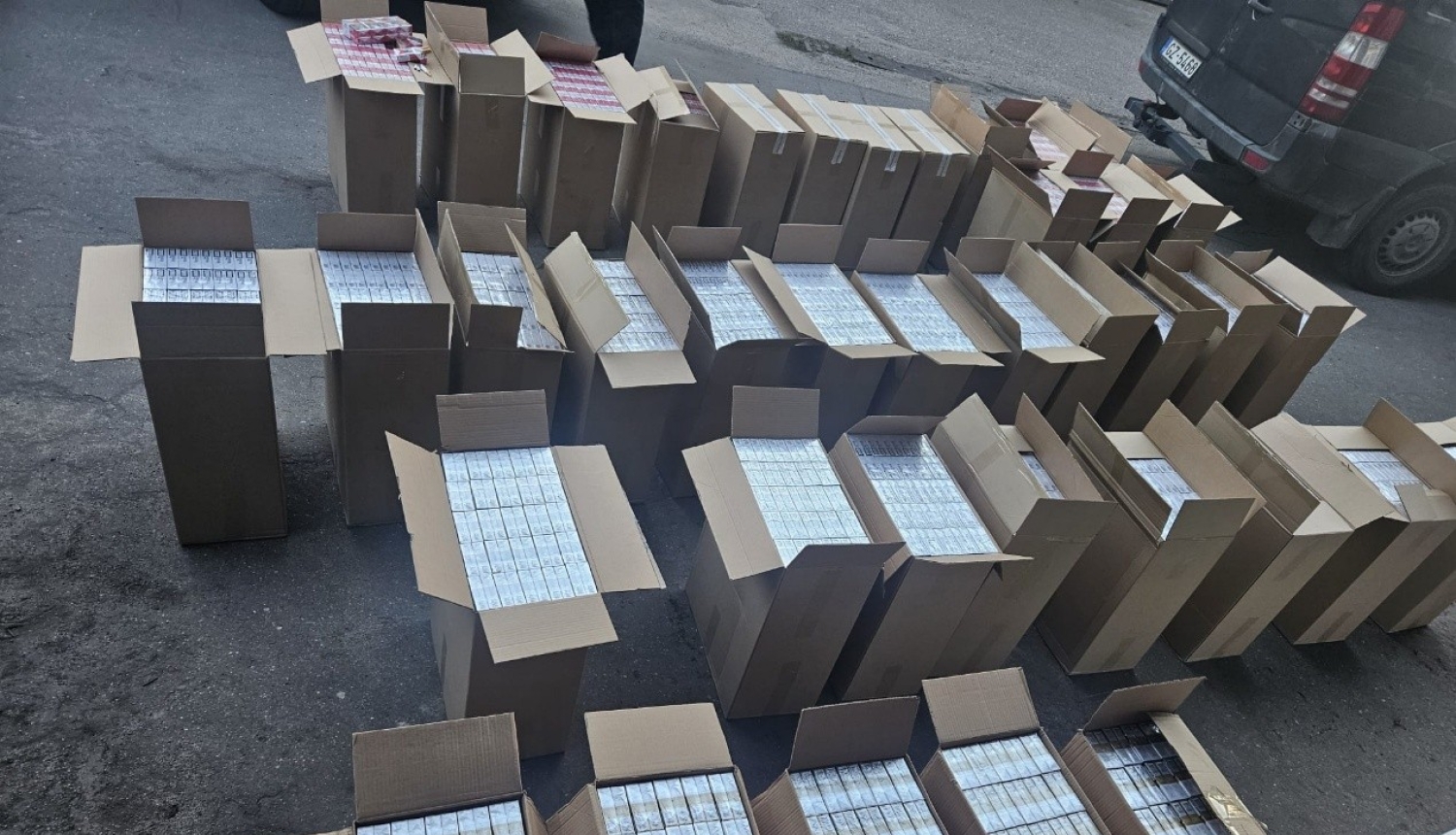 Uz grīdas saliktas daudz atvērtas kartona kastes ar cigarešu paciņām